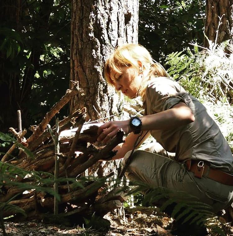 Woman constructing a hidden bushcraft shelter