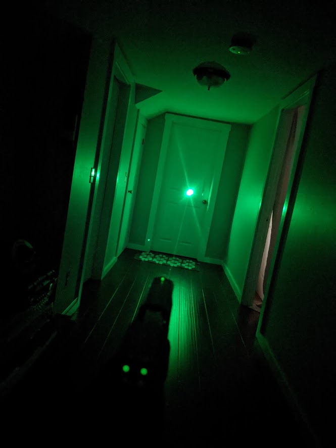 Olight Baldr Pro's green laser on a dark hallway.
